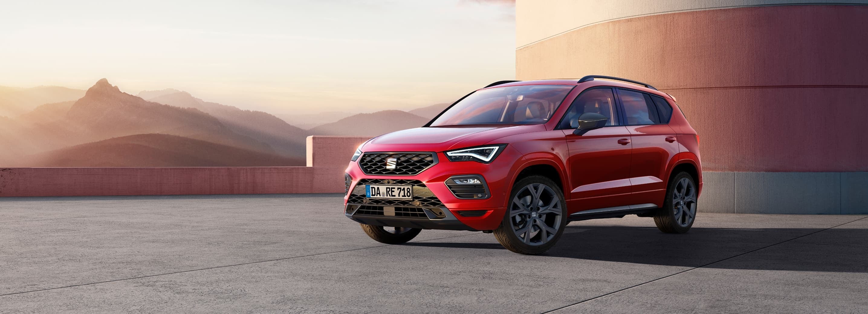 Roter SEAT Ateca in Frontansicht auf offenem Platz vor moderner Architektur