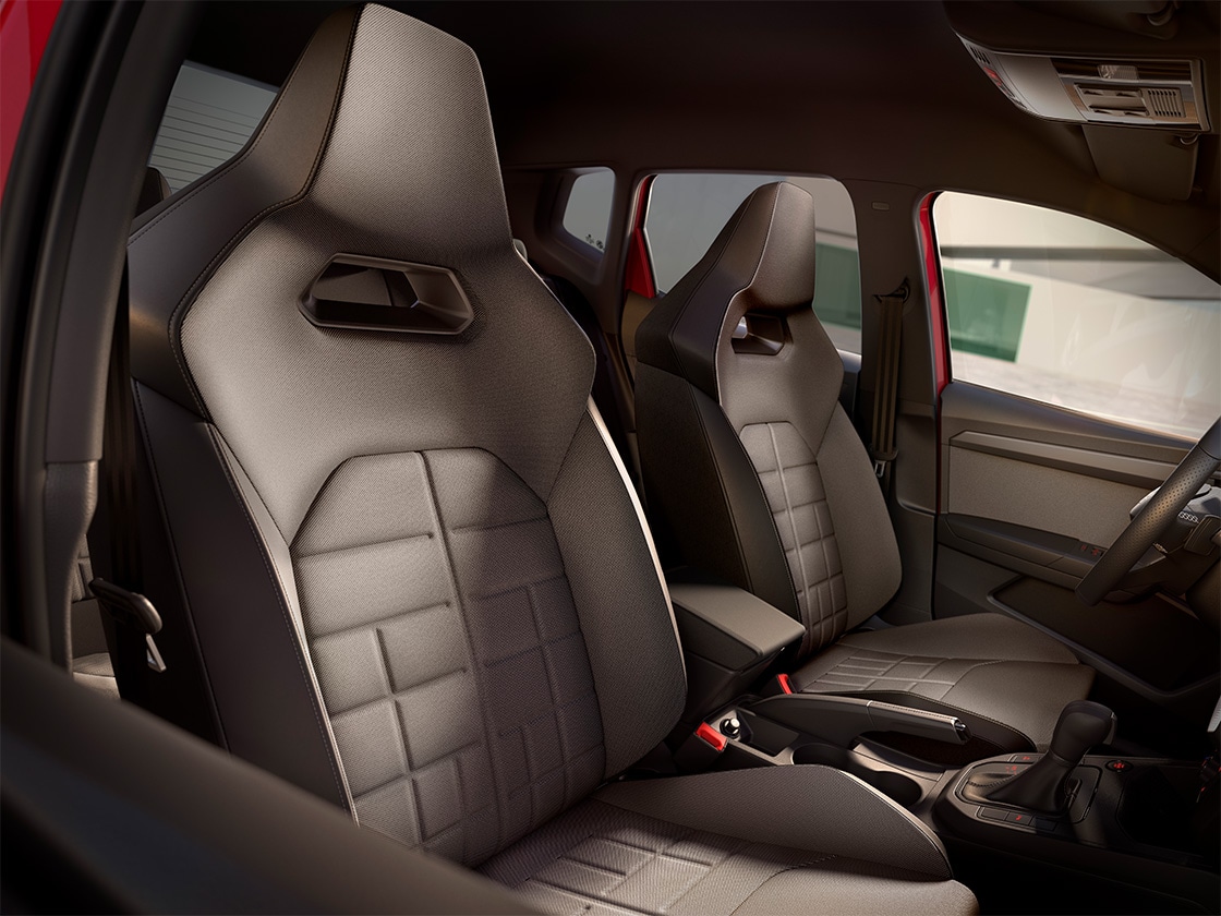 Vordersitze eines Autos mit gepolsterten Sitzen und sportlichem Design, Armlehne und Schalthebel in der Mittelkonsole, machtvoller Lichteinfall durch das Schiebedach, schwarze Innenverkleidung, roter Fahrzeugrahmen erkennbar.