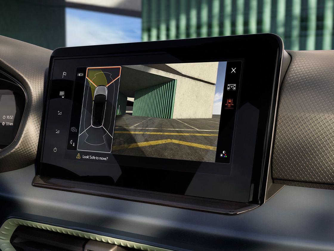 Nahaufnahme eines Autoinnenraums mit Fokus auf den Bildschirm des Infotainmentsystems. Auf dem Display wird ein Parkassistenten-Modus angezeigt, mit einer grafischen Darstellung des Autos und der Umgebung. Teile des Armaturenbretts sind sichtbar