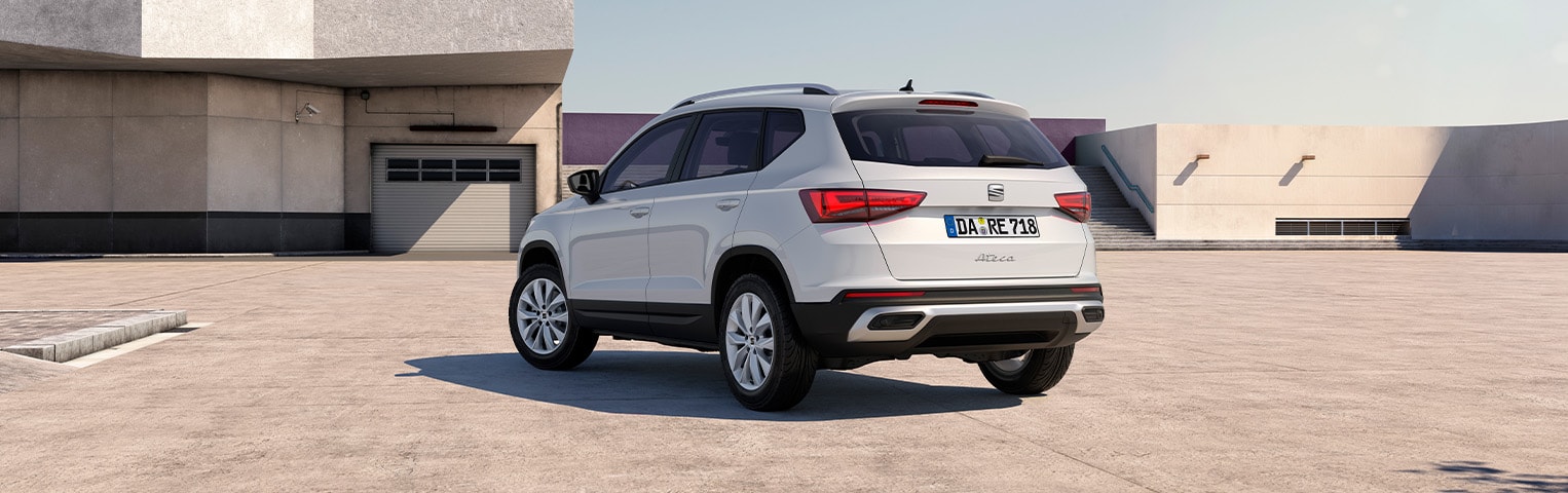 Weißer SEAT Ateca in Heckansicht auf offenem Platz vor moderner Architektur