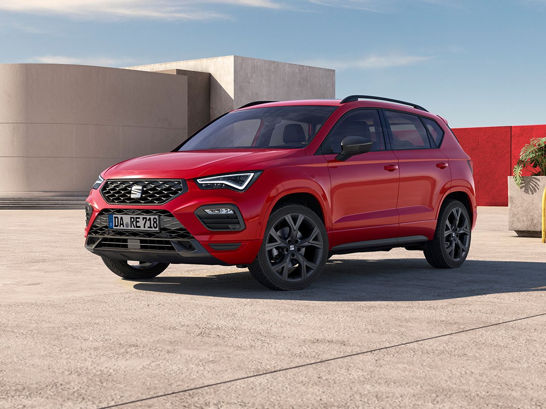 Roter SEAT Ateca FR in schräger Front-Seitenansicht vor moderner Architektur