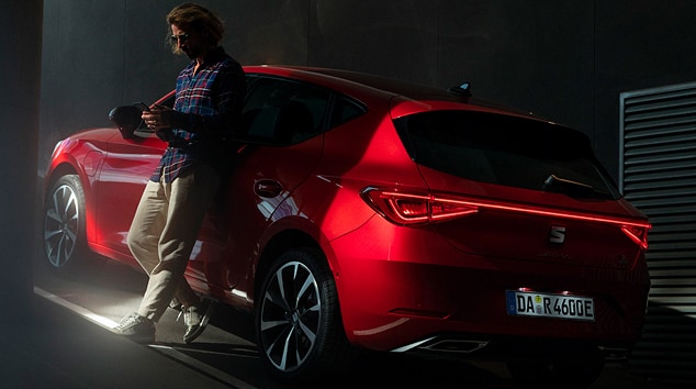 Plug-in-Hybrid-Elektrofahrzeug Seat Leon in Rot, Rückfahrscheinwerfer, Sonnenuntergang und Meer.