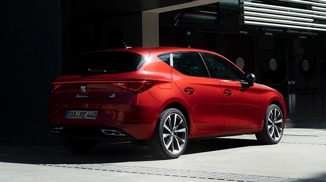 Mild-Hybrid-Elektrofahrzeug SEAT Leon Sportstourer in Rot, im Schatten neben einem Gebäude geparkt