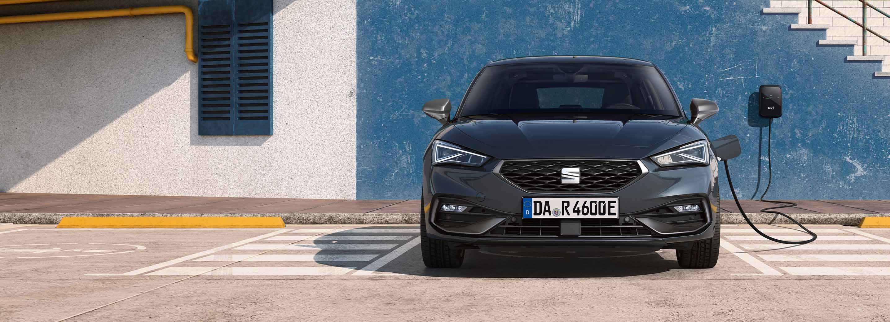 Frontalansicht eines SEAT Leon, während er an einer Wallbox auflädt. 