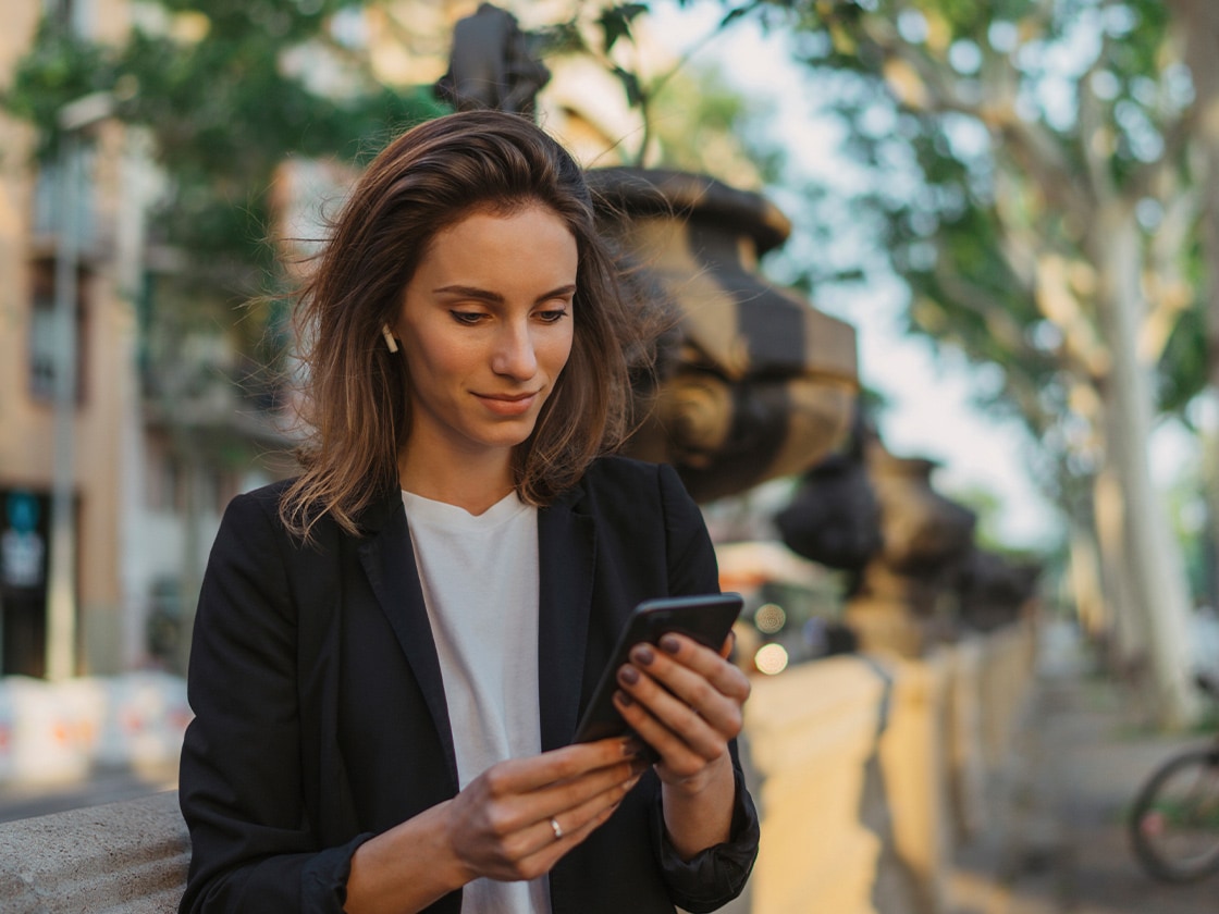 Eine Frau blickt auf auf ihr Smartphone.