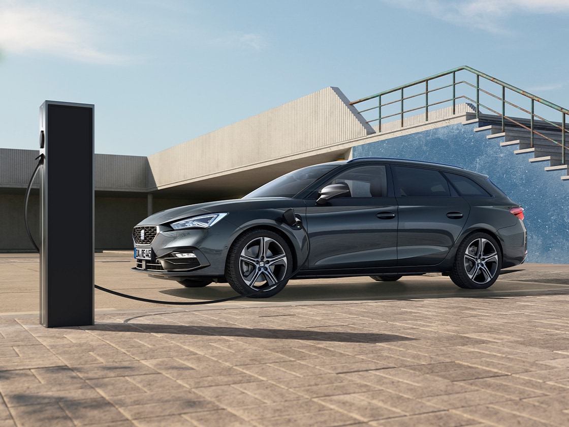 Der SEAT Leon Sportstourer steht an einer Ladesäule und lädt auf. 