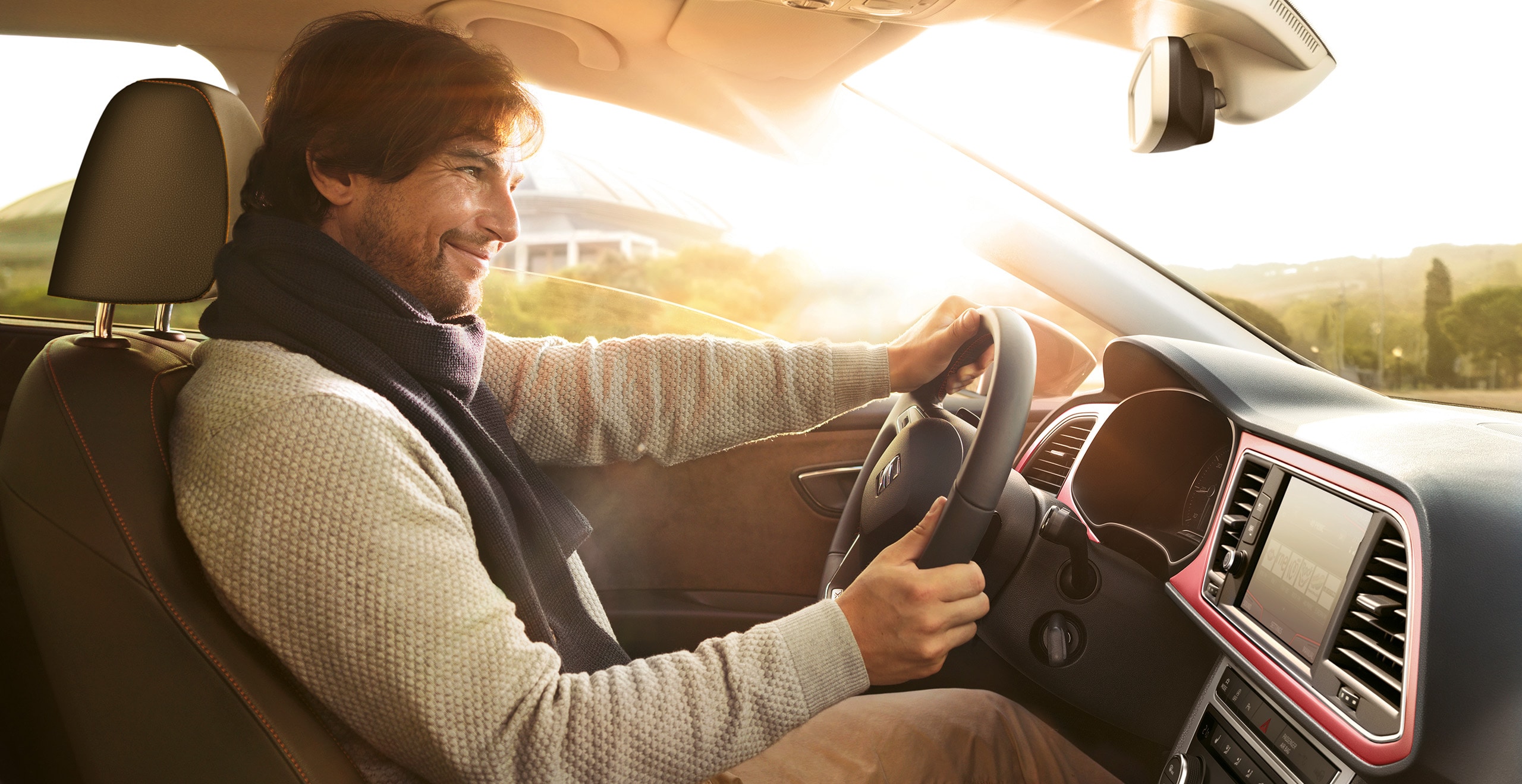 Mann sitzt am Steuer eines SEAT Fahrzeugs, im Hintergrund ist der Sonnenuntergang zu erkennen.