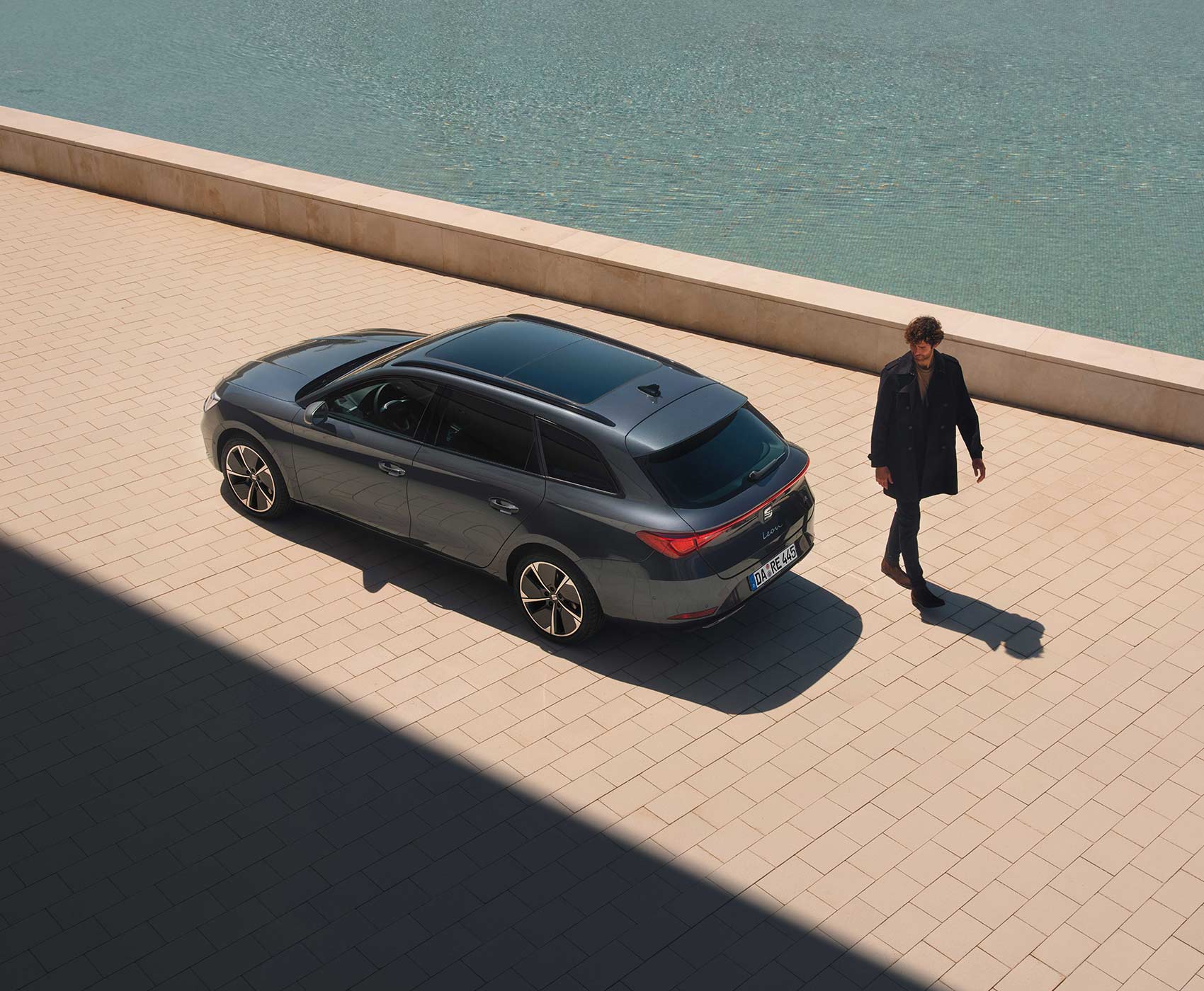 Ein SEAT Leon steht an einer Hafenpromenade, Vogelperspektive. Hinter dem SEAT Leon läuft ein Mann vorbei.