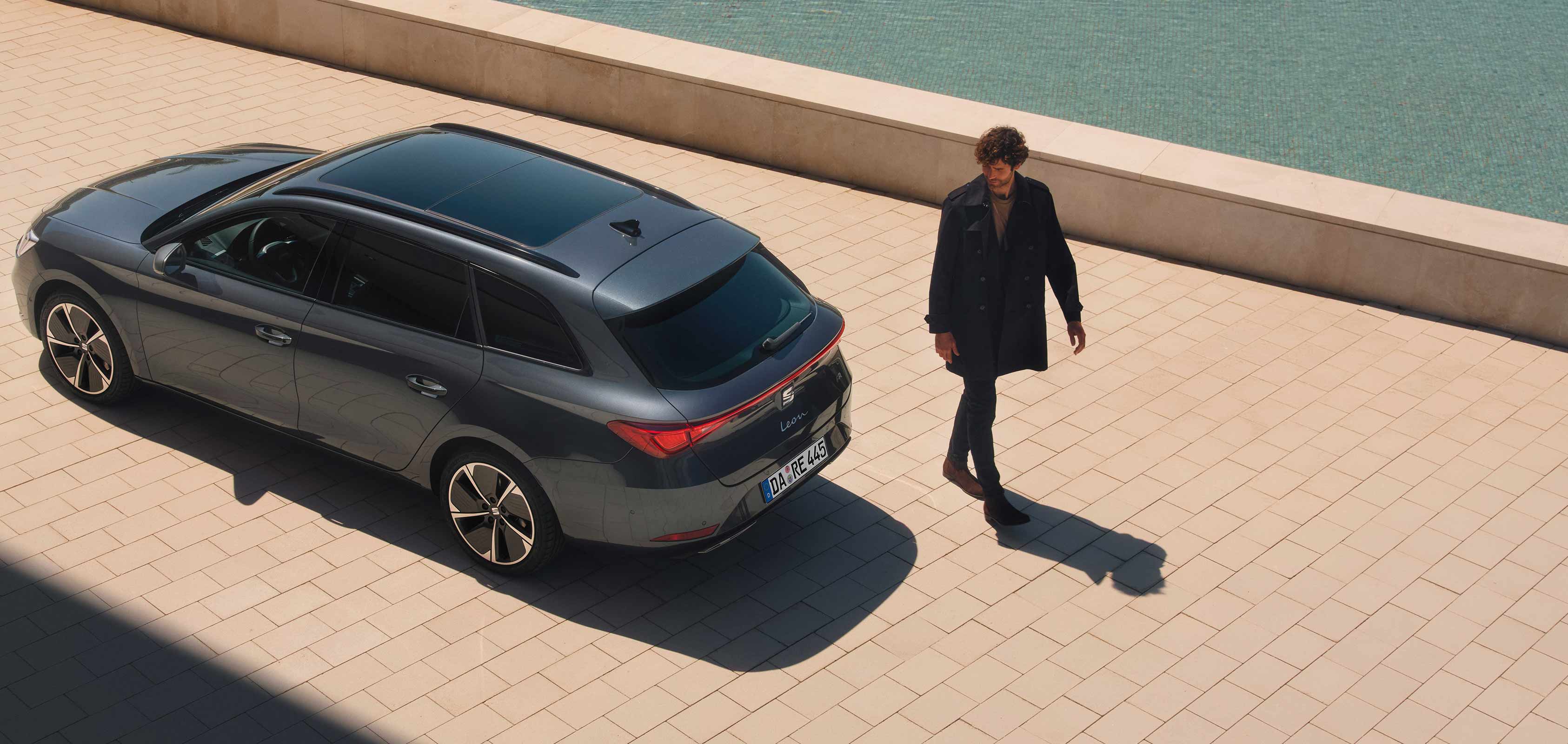Ein SEAT Leon steht an einer Hafenpromenade, Vogelperspektive. Hinter dem SEAT Leon läuft ein Mann vorbei.