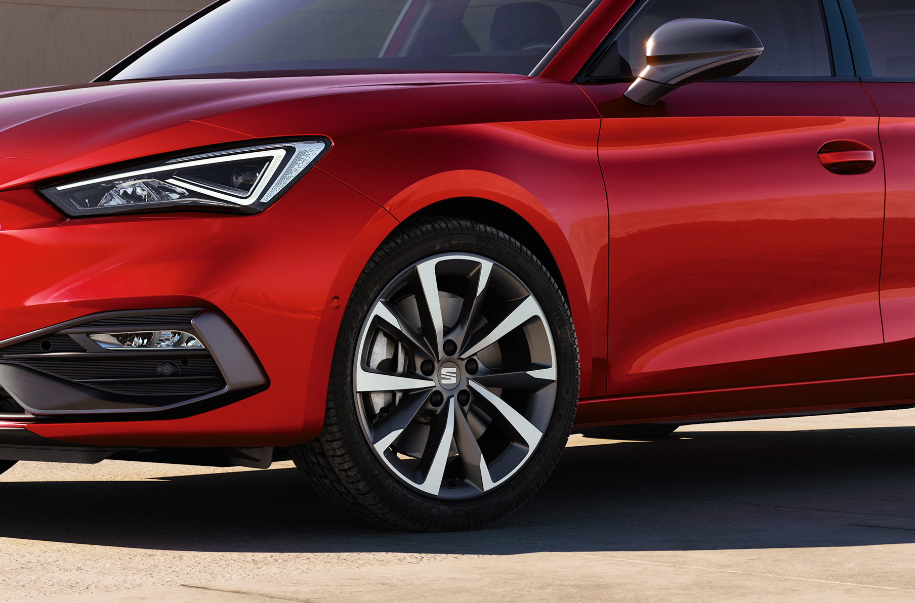 Mann steht neben dem Seat Leon in Rot mit Performance Leichtmetallfelgen