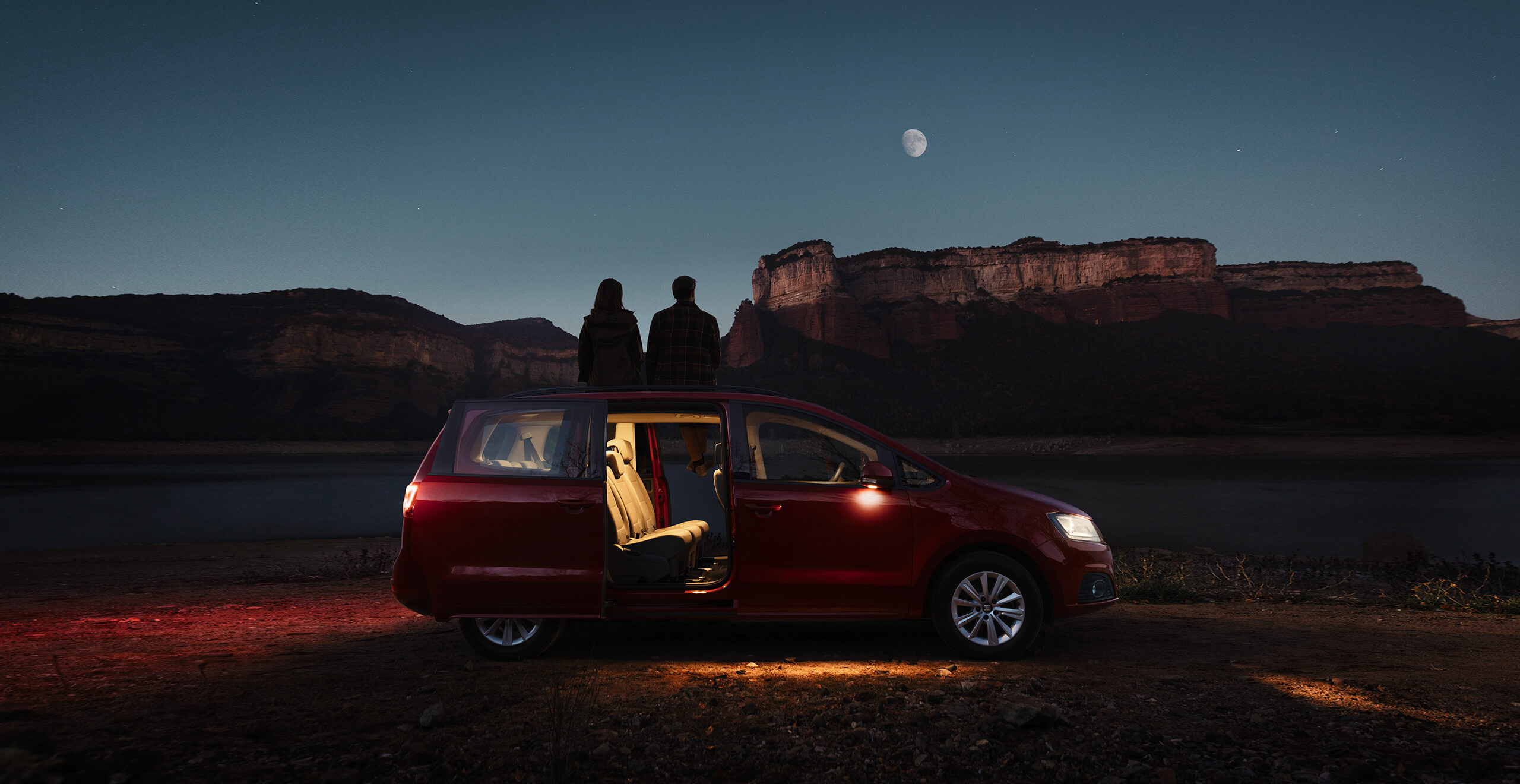 Seitenansicht eines SEAT Alhambra MPV bei Nacht mit offenen Türen und zwei Personen, die den Mond und eine Berglandschaft ansehen | SEAT