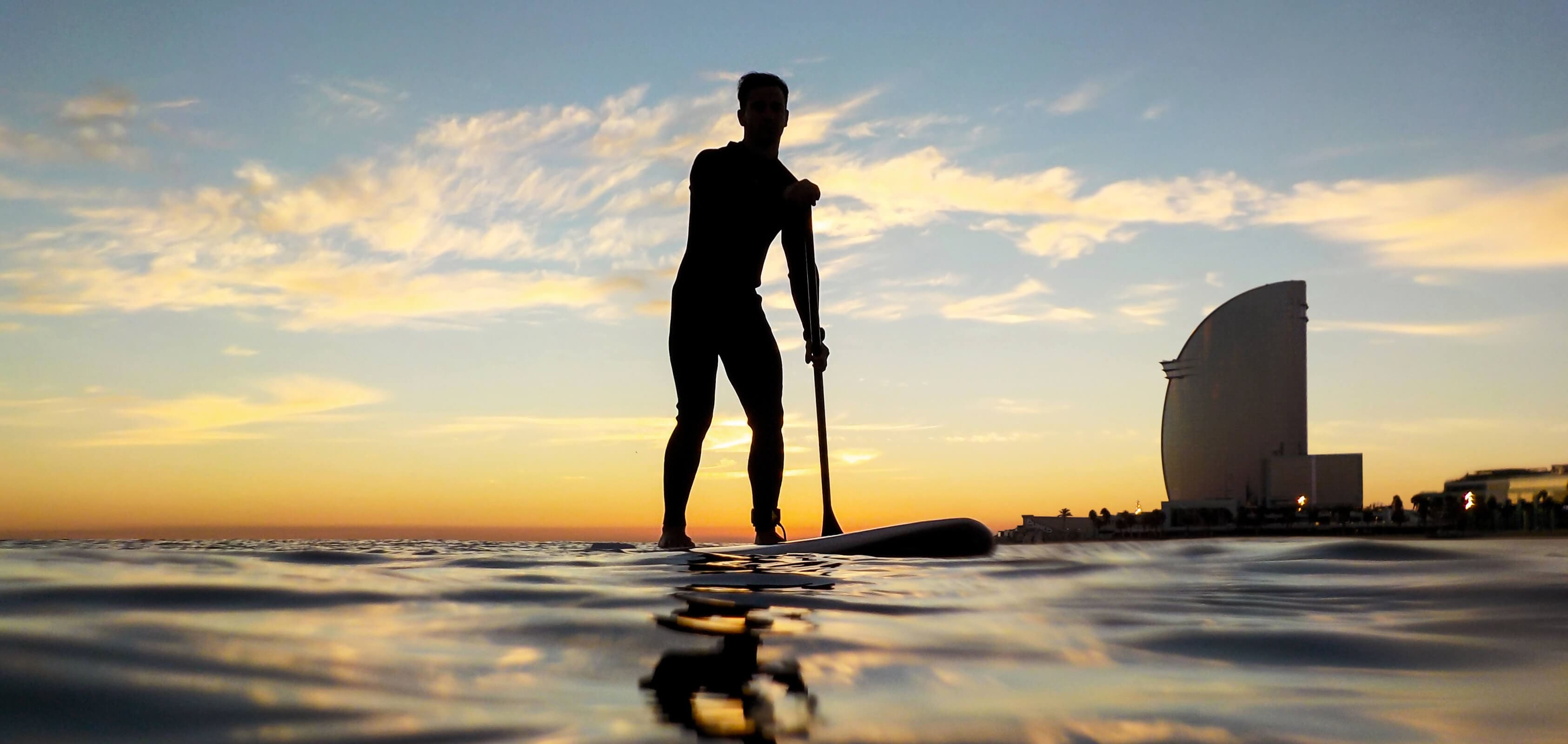 Silhouette eines Mannes beim Stand-up-Paddling am Strand von Barceloneta mit dem W Hotel im Hintergrund | SEAT