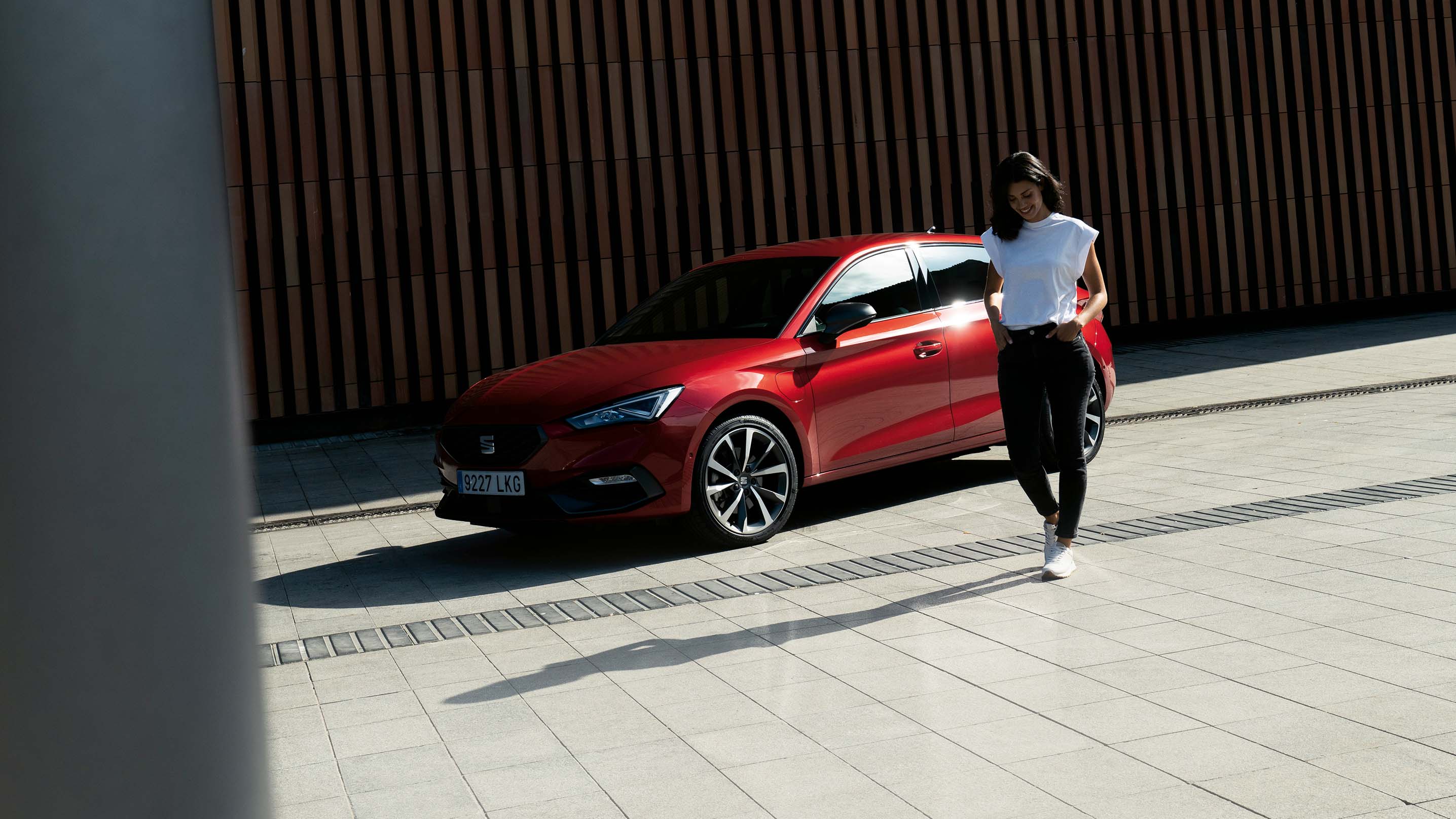 Hybridfahrzeug SEAT Leon in Rot, im Schatten neben einem Gebäude geparkt.