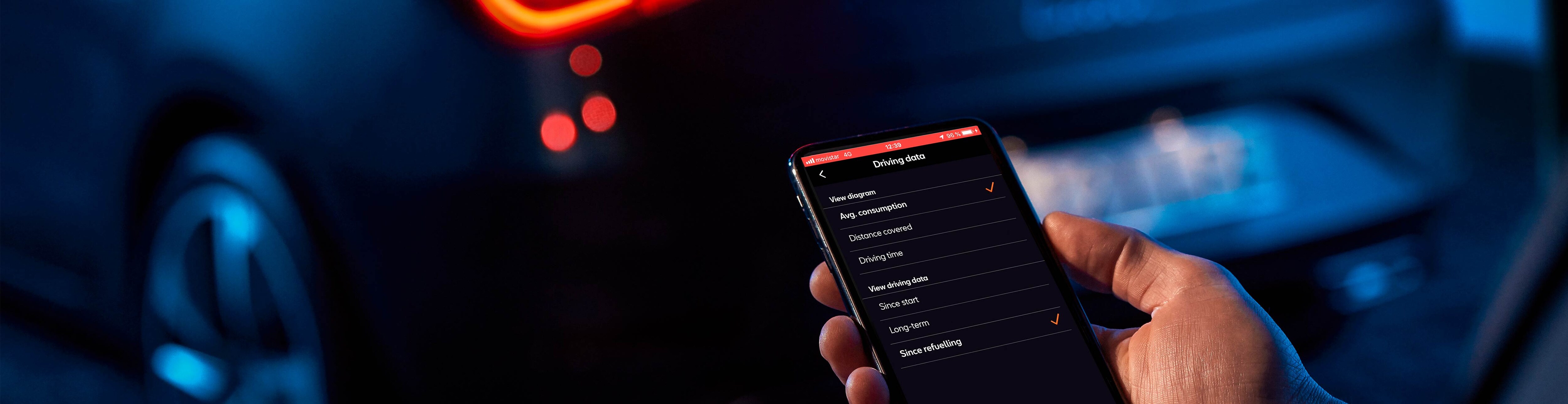 Junger Mann mit Mobiltelefon neben seinem SEAT